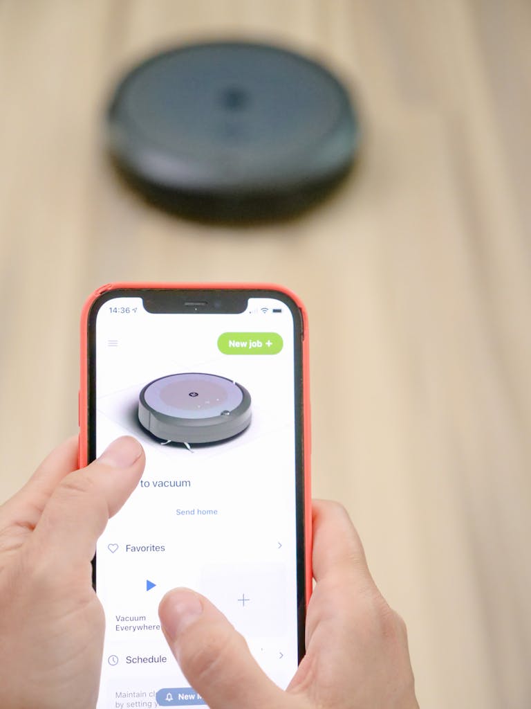 User operates robotic vacuum via smartphone app, showcasing smart home technology.